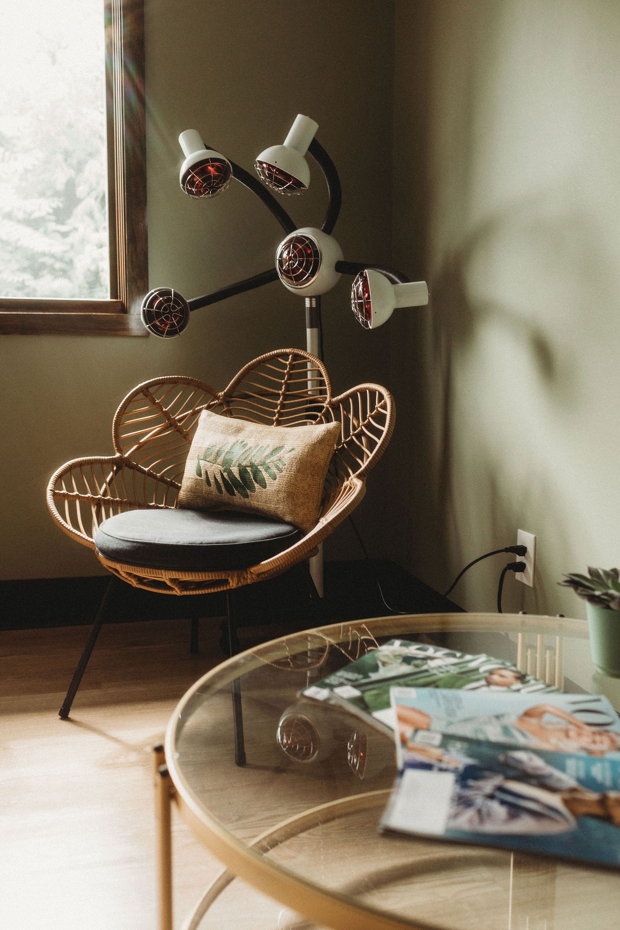Rattan chair, fringed pillow and processing lamp by a sun-lit window