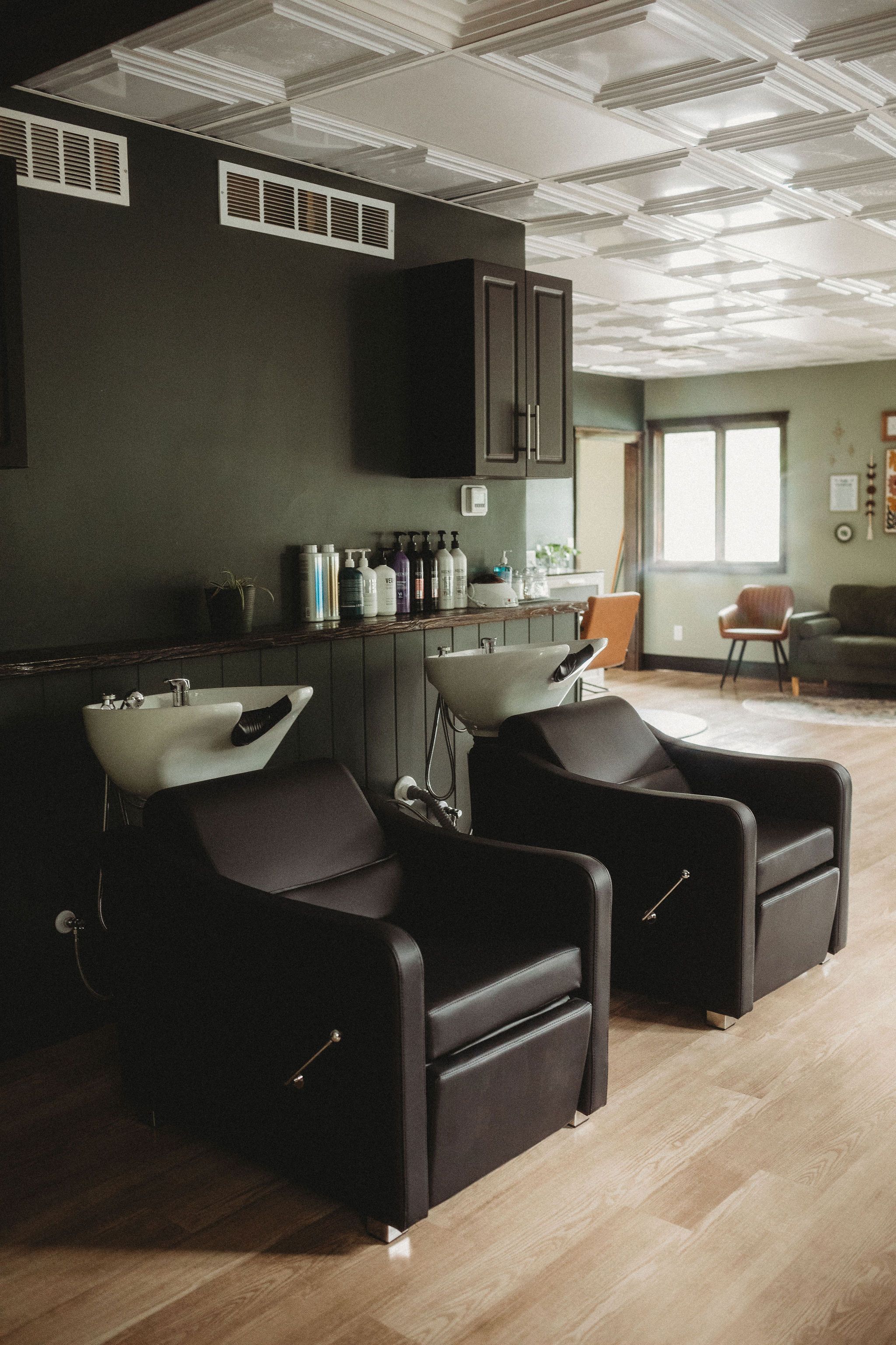Two black wash chairs against a forest-green wall under a pressed-tin ceiling